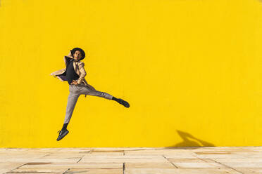 Junger Mann tanzt vor einer gelben Wand und springt in der Luft - AFVF04551