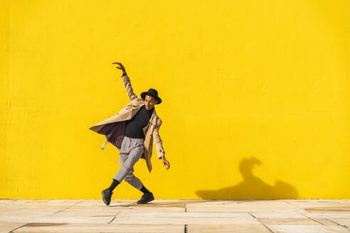 Young man dancing in front of yellow wall - AFVF04554