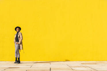 Young man dancing in front of yellow wall - AFVF04556