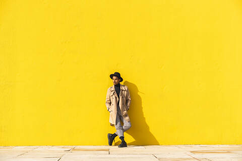 Junger Mann tanzt vor einer gelben Wand, lizenzfreies Stockfoto