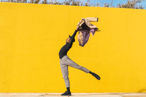 Junger Mann tanzt vor einer gelben Wand - AFVF04583