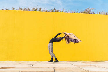 Junger Mann tanzt vor einer gelben Wand - AFVF04584