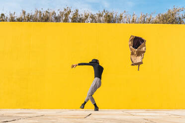 Young man dancing in front of yellow wall - AFVF04585