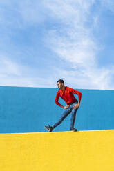 Young man dancing on yellow wall - AFVF04600