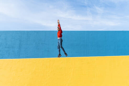 Young man with headphones, listening music, dancing on yellow wall - AFVF04606