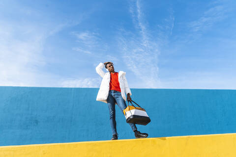 Young trendy man standing on yellow wall, listening music stock photo