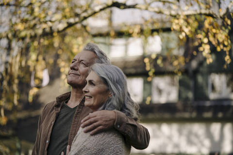 Affectionate senior couple in garden of their home in autumn stock photo