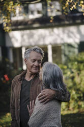 Affectionate senior couple in garden of their home in autumn - GUSF02974