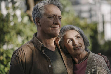 Portrait of confident senior couple in garden of their home in autumn - GUSF02977