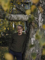 Portrait of a senior man at tree in garden - GUSF02988