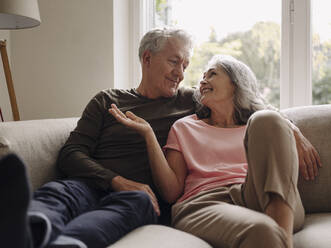 Happy senior couple relaxing on couch at home - GUSF03000