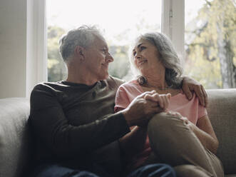 Affectionate senior couple relaxing on couch at home - GUSF03004