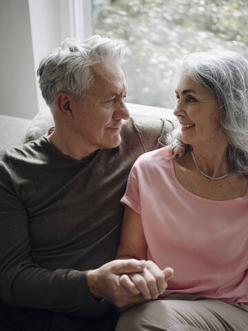 Affectionate senior couple relaxing on couch at home stock photo