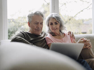 Älteres Paar mit Laptop, das sich zu Hause auf der Couch entspannt - GUSF03007
