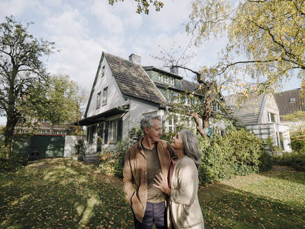 Senior couple in garden of their home in autumn - GUSF03017