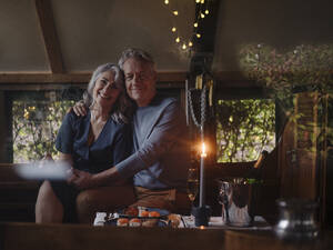 Portrait of senior couple having a candlelight dinner on a boat in boathouse - GUSF03028