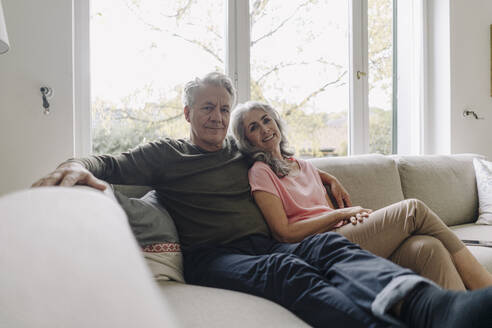 Porträt eines älteren Paares, das sich zu Hause auf der Couch entspannt - GUSF03036