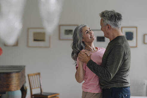 Happy senior couple dancing in living room at home - GUSF03053