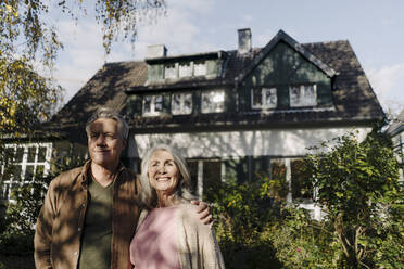 Älteres Ehepaar im Garten ihres Hauses im Herbst - GUSF03065