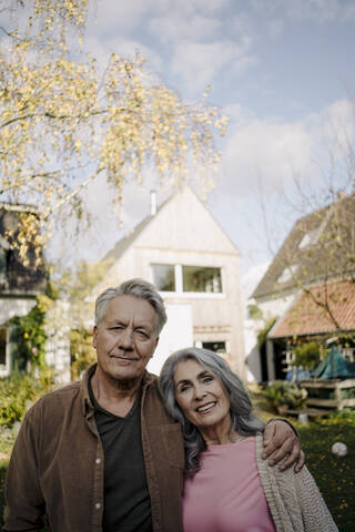 Porträt eines älteren Paares im Garten ihres Hauses im Herbst, lizenzfreies Stockfoto