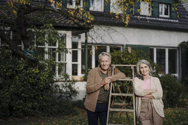 Porträt eines älteren Paares mit einer Leiter im Garten ihres Hauses - GUSF03076