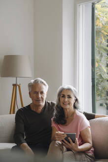 Porträt eines älteren Paares, das sich zu Hause auf der Couch entspannt - GUSF03108