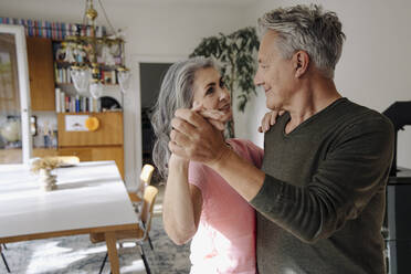 Senior couple dancing in living room at home - GUSF03116