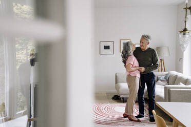 Älteres Ehepaar steht im Wohnzimmer zu Hause - GUSF03120