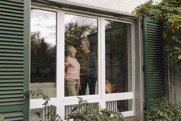 Senior couple behind windowpane of their home - GUSF03127