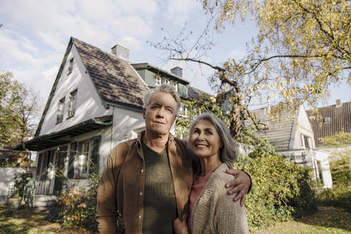 Älteres Ehepaar im Garten ihres Hauses im Herbst - GUSF03132