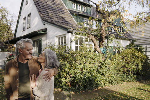 Senior couple in garden of their home in autumn - GUSF03134