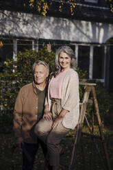 Älteres Ehepaar mit einer Leiter im Garten ihres Hauses - GUSF03146