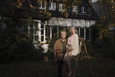 Älteres Ehepaar mit einer Leiter im Garten ihres Hauses, lizenzfreies Stockfoto
