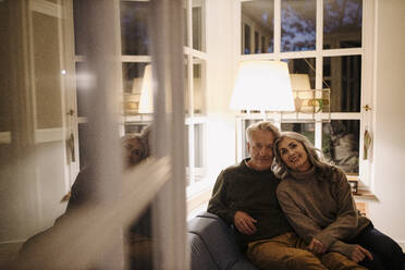 Portrait of senior couple relaxing on couch at home at night - GUSF03165