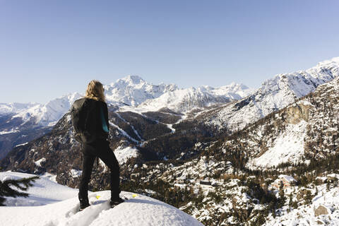 Frau, die mit Schneeschuhen auf einem Aussichtspunkt steht, Valmalenco, Italien, lizenzfreies Stockfoto