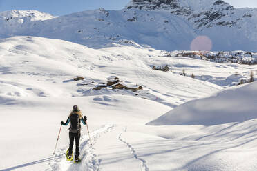 Frau geht mit Schneeschuhen im Neuschnee in den Bergen, Valmalenco, Italien - MRAF00473