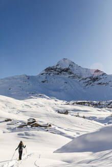 Frau geht mit Schneeschuhen im Neuschnee in den Bergen, Valmalenco, Italien - MRAF00474
