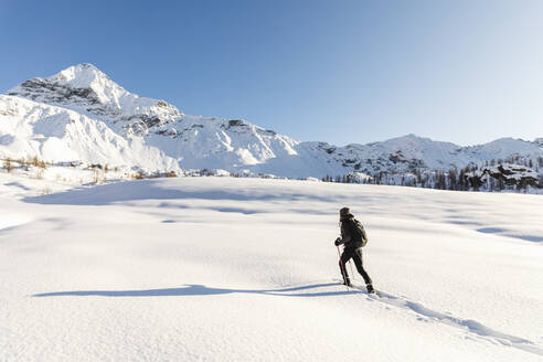 Frau geht mit Schneeschuhen im Neuschnee in den Bergen, Valmalenco, Italien - MRAF00475