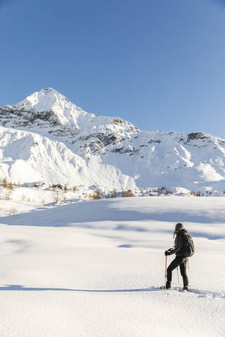 Woman walking with snowshoes in fresh snow in the mountains, Valmalenco, Italy stock photo