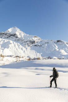 Frau geht mit Schneeschuhen im Neuschnee in den Bergen, Valmalenco, Italien - MRAF00476