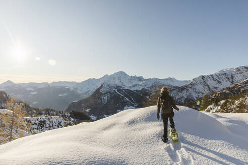 Frau geht mit Schneeschuhen im Neuschnee in den Bergen, Valmalenco, Italien - MRAF00478