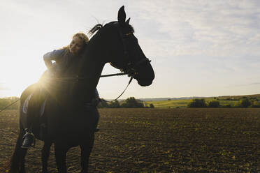 Affectionate woman on horse on a field in the countryside - JOSF04124