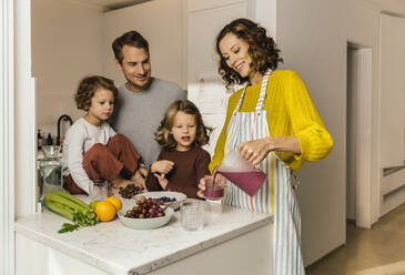 Mother preparing a smoothie for her family in kitchen - MFF04936