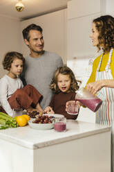 Mother preparing a smoothie for her family in kitchen - MFF04937