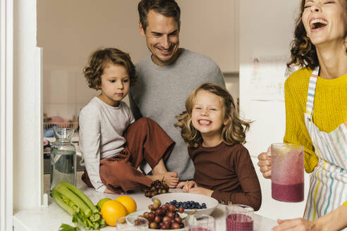 Glückliche Familie bei der Zubereitung eines Smoothies in der Küche - MFF04938