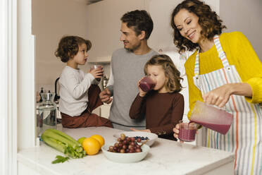 Mother preparing a smoothie for her family in kitchen - MFF04939