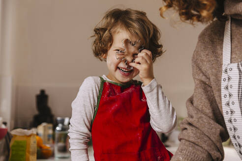 Verspieltes Mädchen mit ihrer Mutter, die in der Küche Weihnachtsplätzchen ausstechen - MFF04944