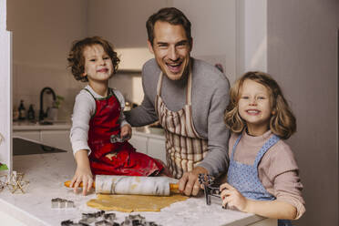 Happy father with two daughters preparing Christmas cookies in kitchen - MFF04946