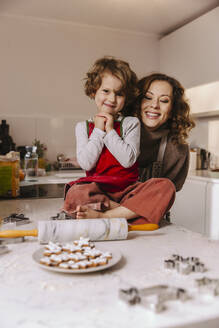 Porträt einer glücklichen Mutter und einer Tochter mit Weihnachtsgebäck in der Küche - MFF04960