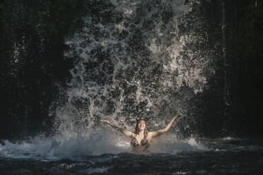 Junge Frau in der Nähe eines Wasserfalls, Bali, Indonesien - KNTF03770